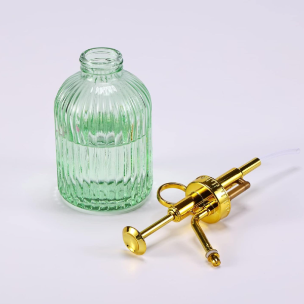 Green glass mister with a gold colored pump head