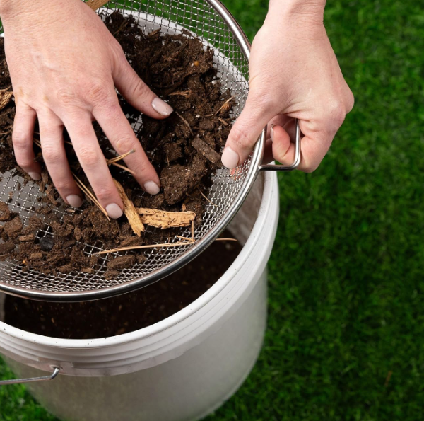 Round stainless steel garden sieve with handle, designed for filtering fine soil and compost